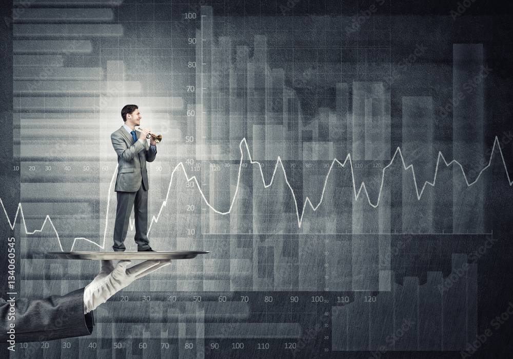 Young businessman on metal tray playing fife against concrete background with chart