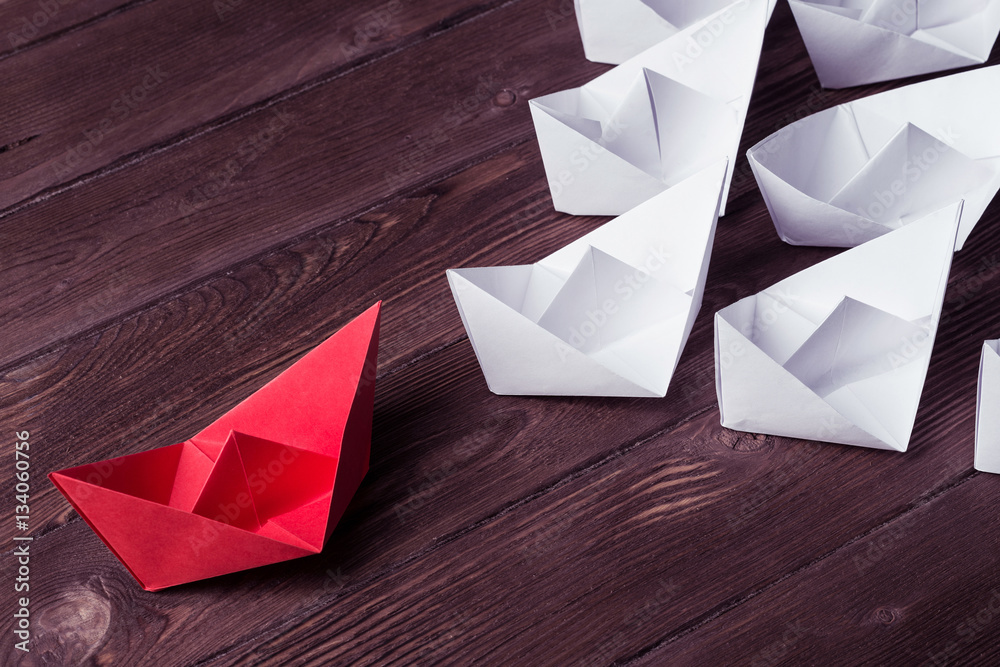 Business leadership concept with white and color paper boats on 