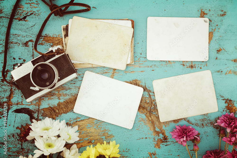 Retro camera and empty old instant paper photo album on wood table with flowers border design - conc