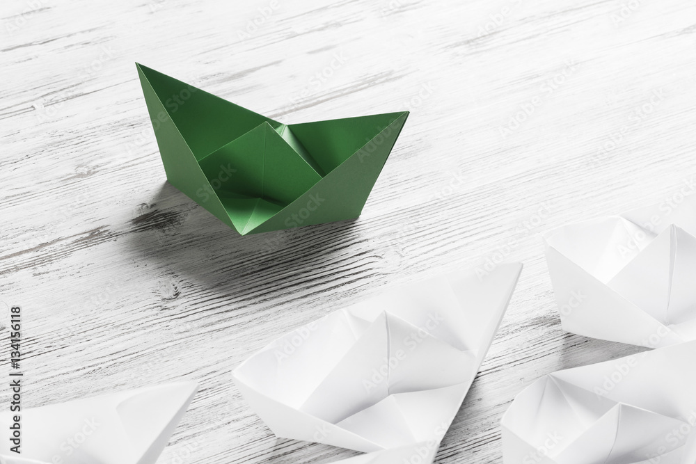 Business leadership concept with white and color paper boats on 