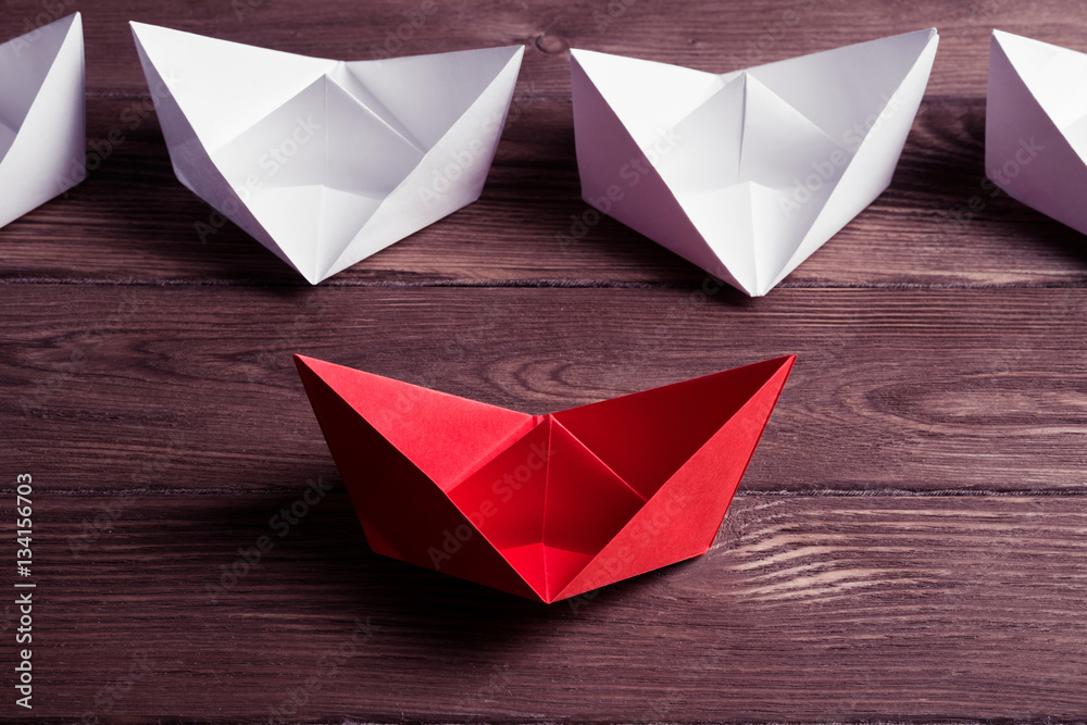 Business leadership concept with white and color paper boats on 