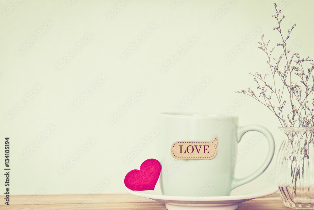 Coffee cup mug with red heart shapeand love word tag 