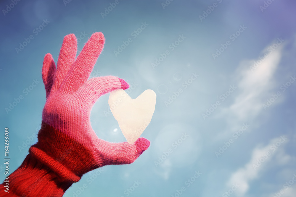 Hand in Pink striped glove holding a snow heart