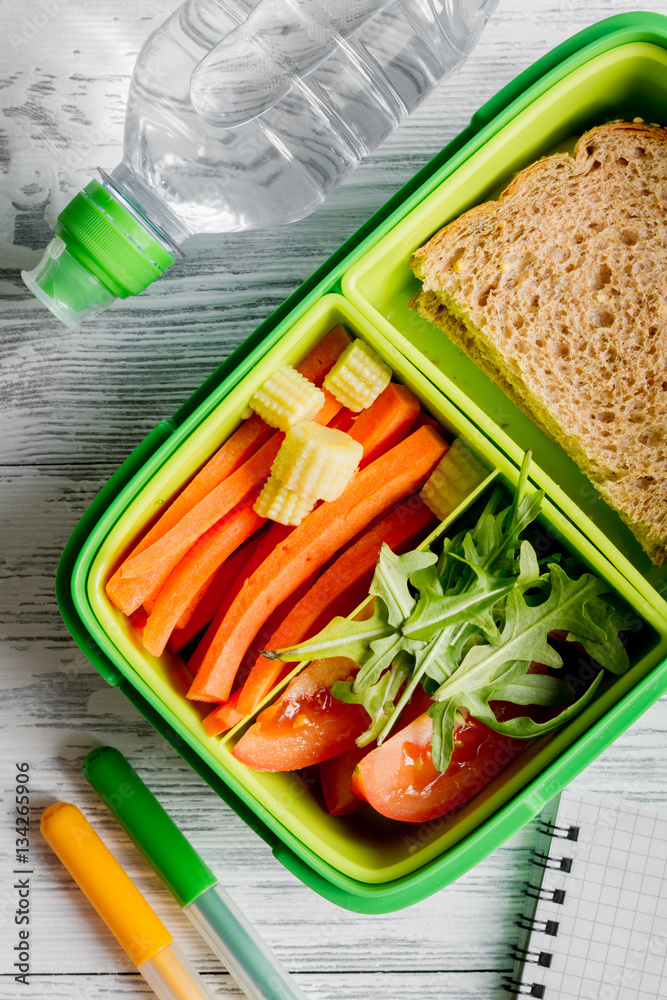 green lunch box for kid on wooden background top view