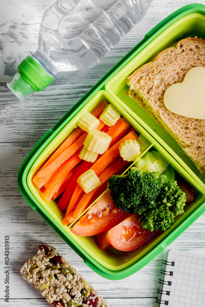 green lunch box for kid on wooden background top view