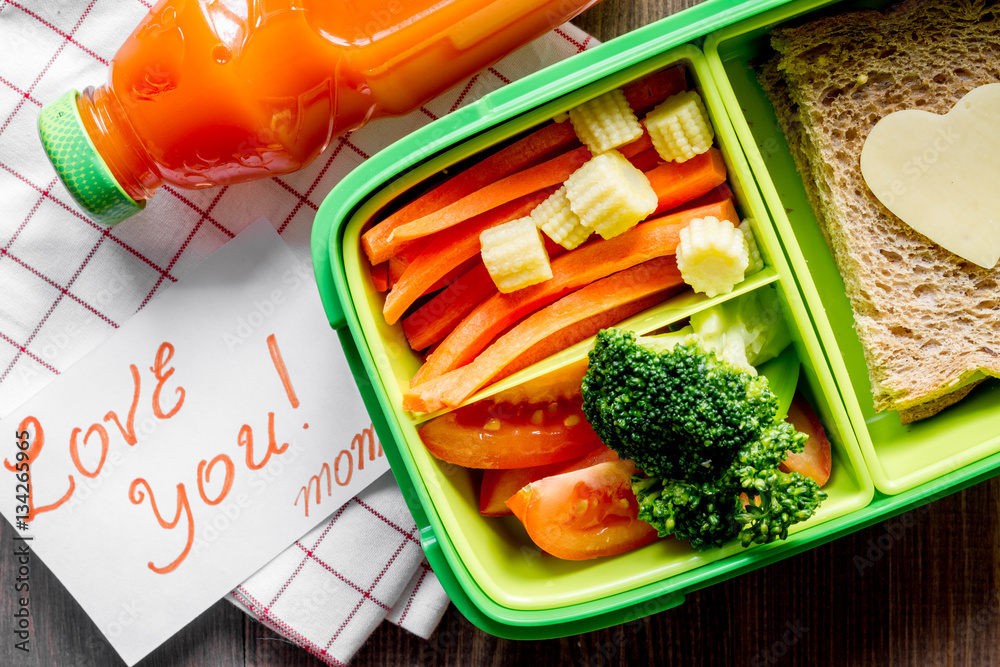 green lunch box for kid on wooden background top view