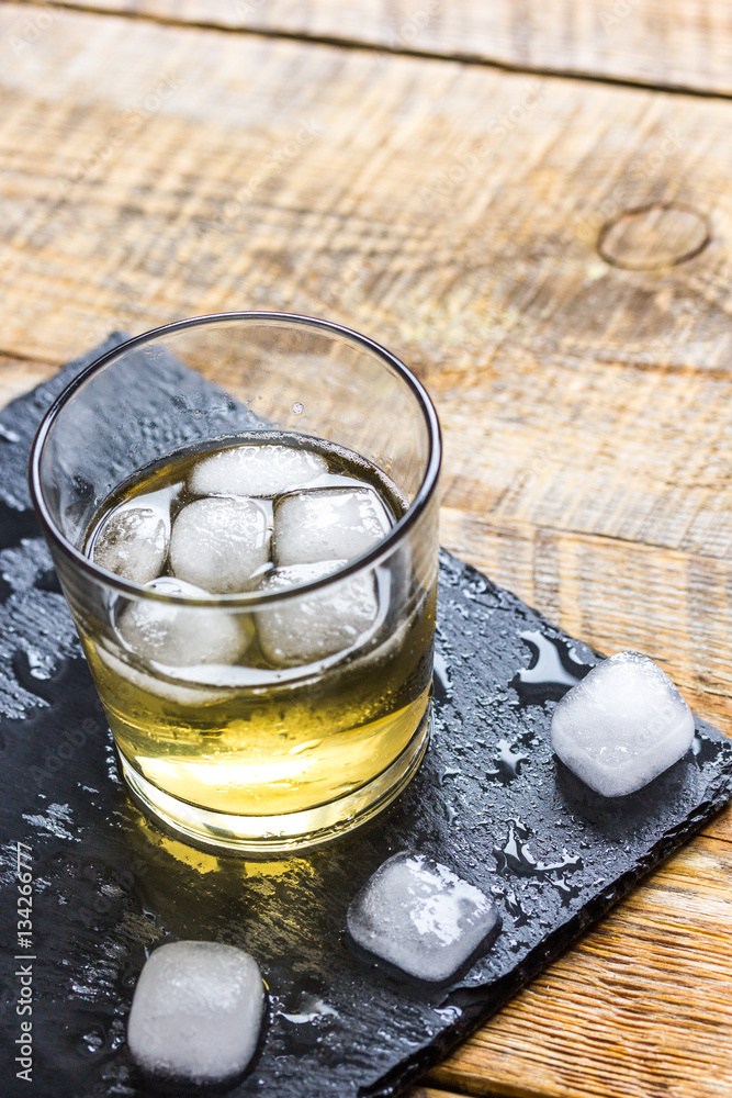 glass of whiskey on wooden background