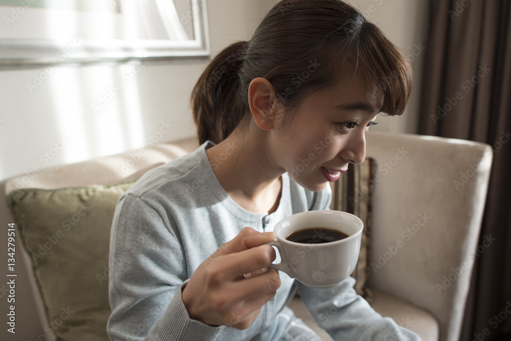 一个年轻女人坐在沙发上喝咖啡