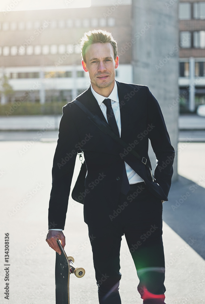 Confident man wearing suit standing with skateboard