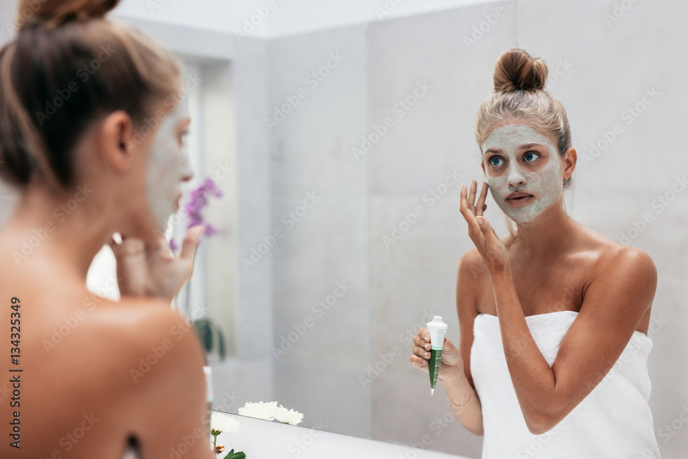 Beautiful woman applying mask to her face