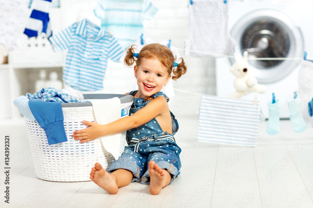 child fun happy little girl to wash clothes in laundry room