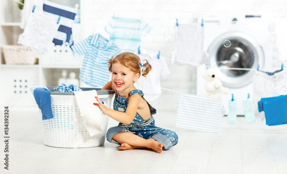 child fun happy little girl to wash clothes in laundry room