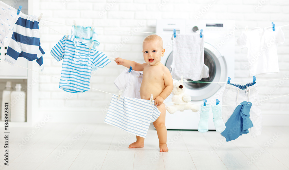 fun happy baby boy to wash clothes and laughs in laundry