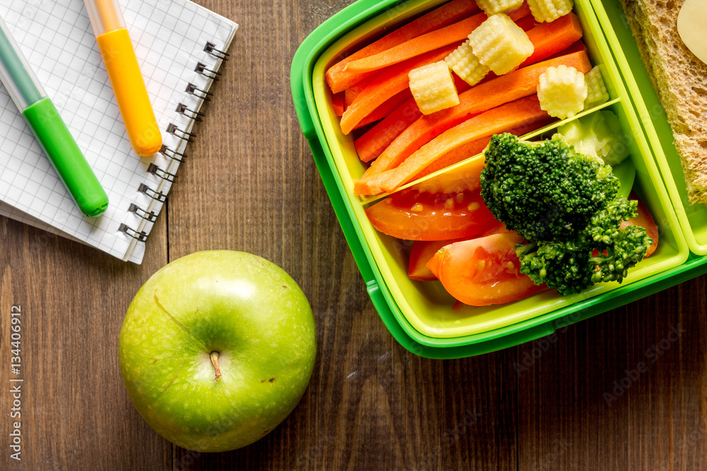 green lunch box for kid on wooden background top view