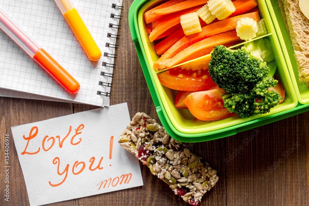 green lunch box for kid on wooden background top view