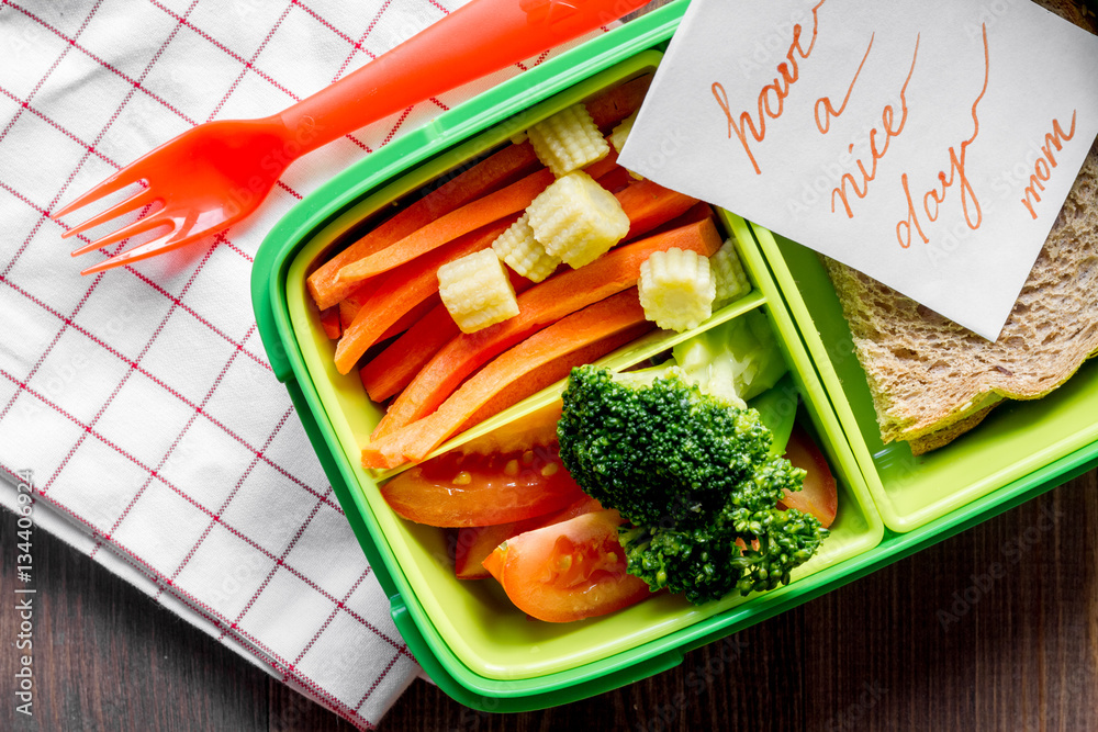 green lunch box for kid on wooden background top view