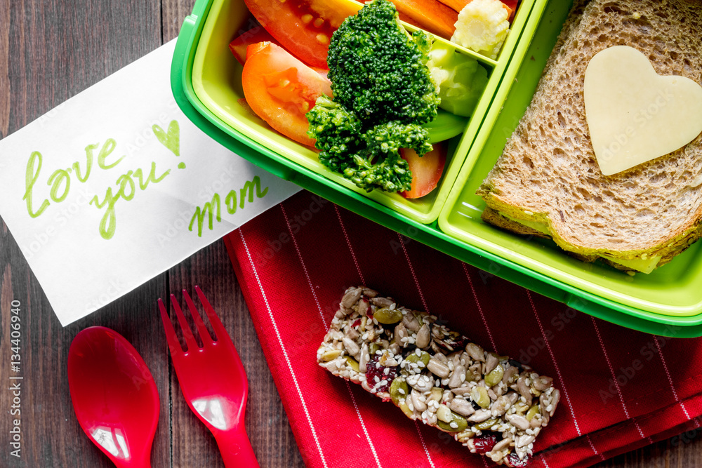 green lunch box for kid on wooden background top view