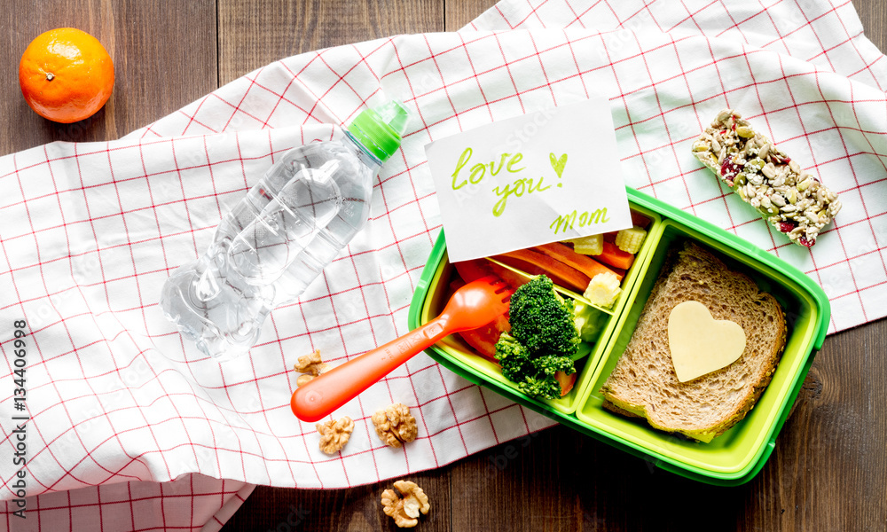 green lunch box for kid on wooden background top view