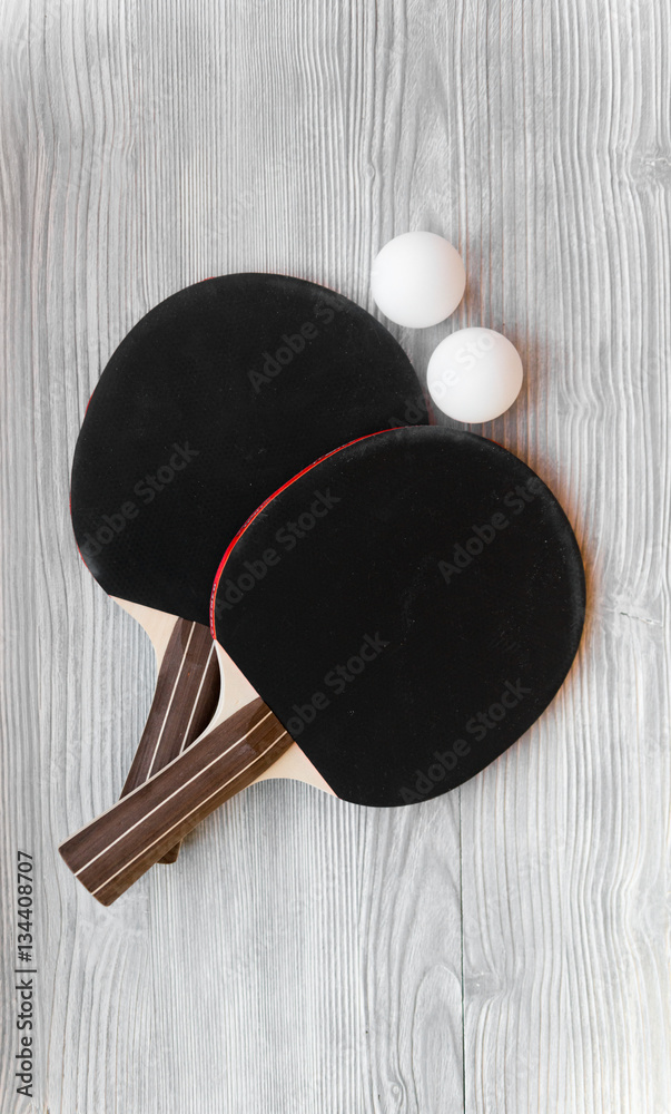 black racket for ping pong ball wooden background top view