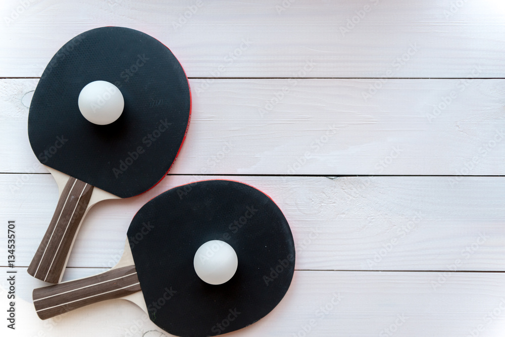 black racket for ping pong ball wooden background top view