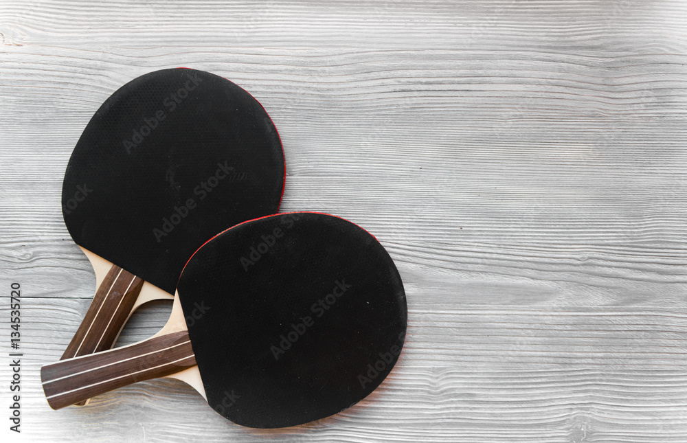 black racket for ping pong ball wooden background top view