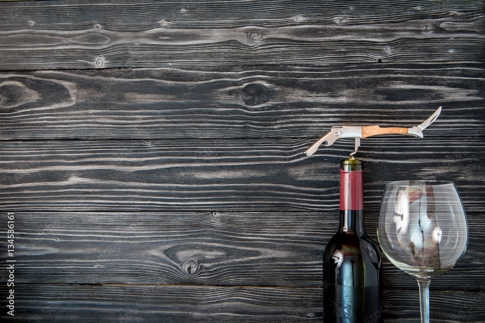 glass wine bottle and corkscrew on wooden background top view