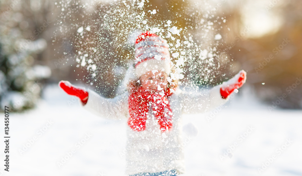 happy child throws up snow on a winter walk