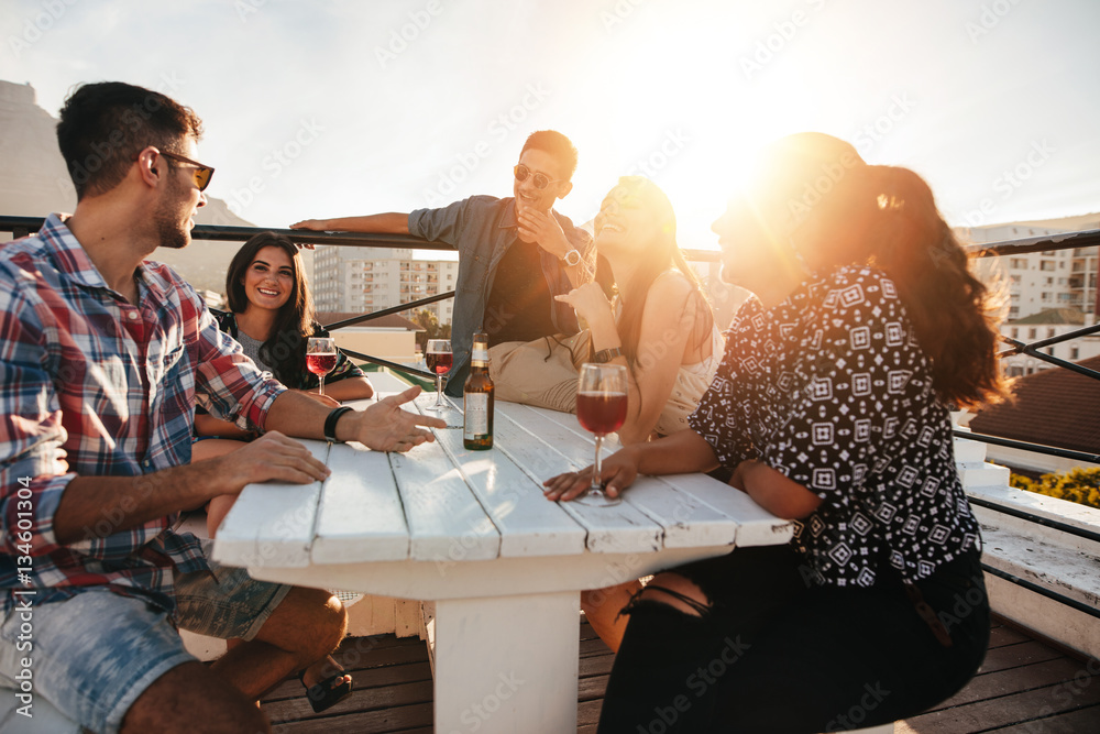 Young people having rooftop party in evening.