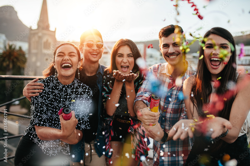 Friends enjoying party and  throwing confetti