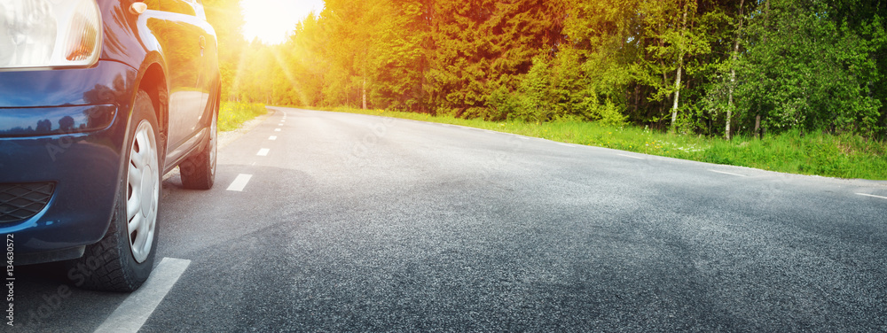 Car on asphalt road on summer day at park. Transportation panoramic background with sunlight