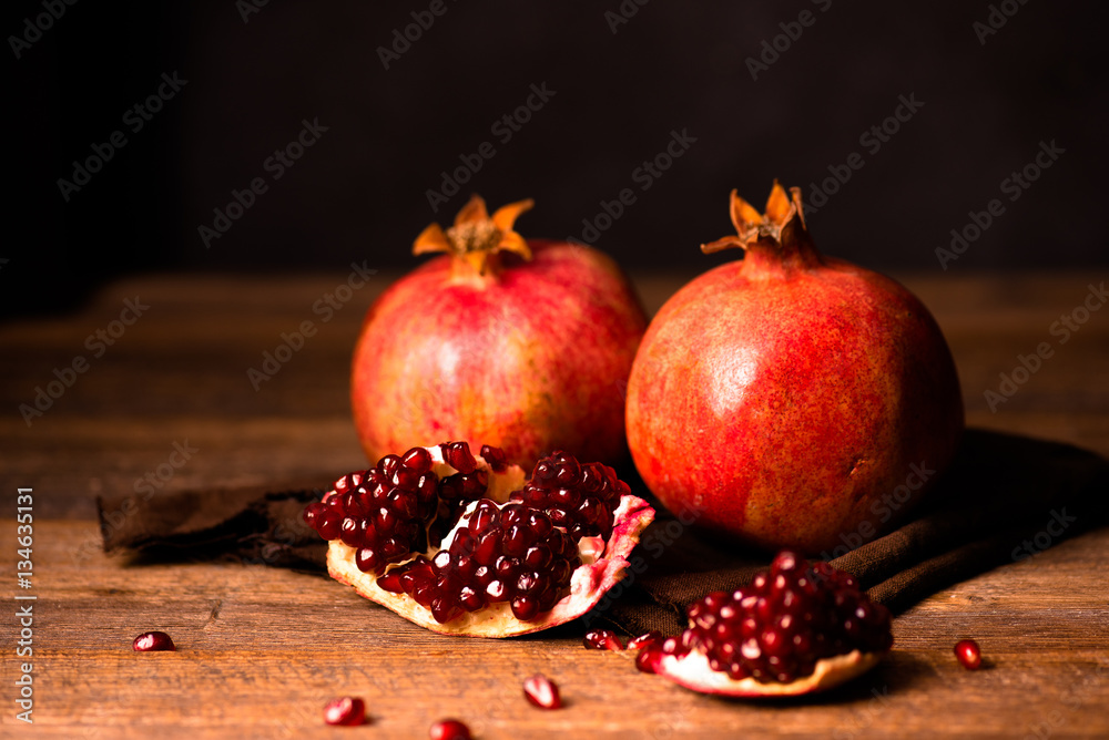 Pomegranate fruits with grains on wooden table. Dark moody. Life style.