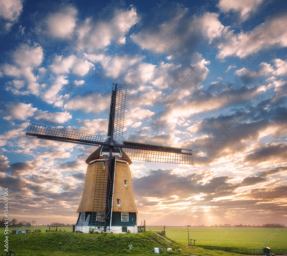 Windmill at sunrise in Netherlands. Beautiful old dutch windmill against colorful sky with clouds. S