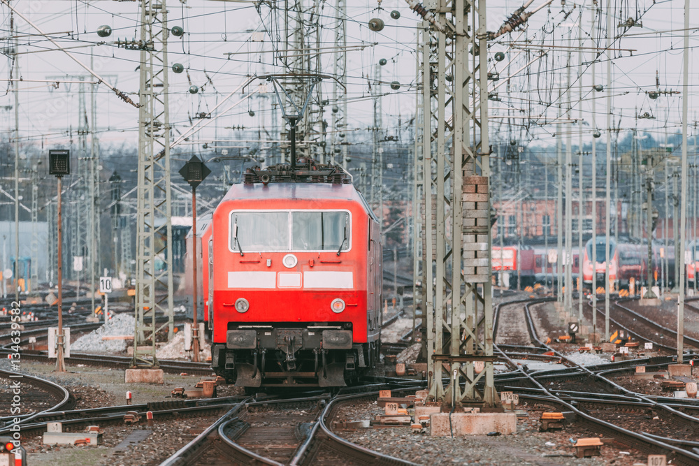 Railway station with modern red commuter train at sunset