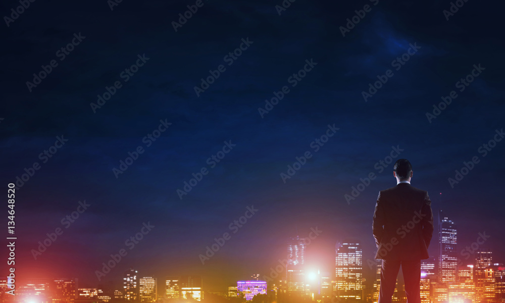 Businessman viewing night glowing city