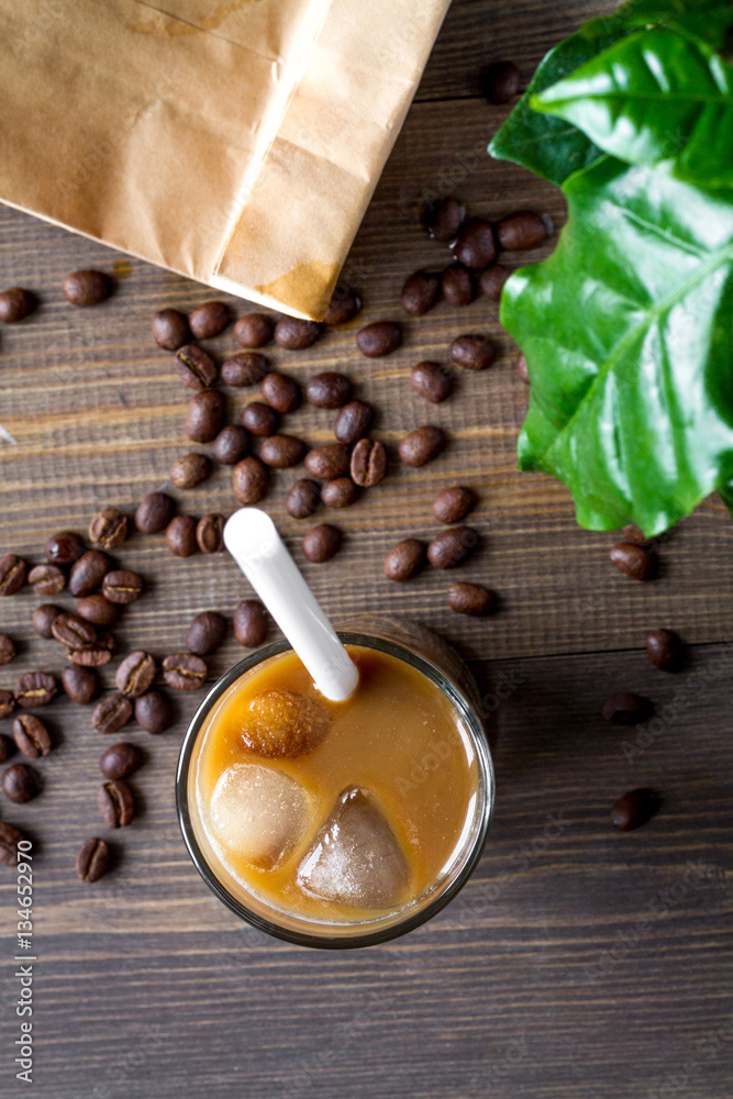 coffee with ice in glass on wooden background top view