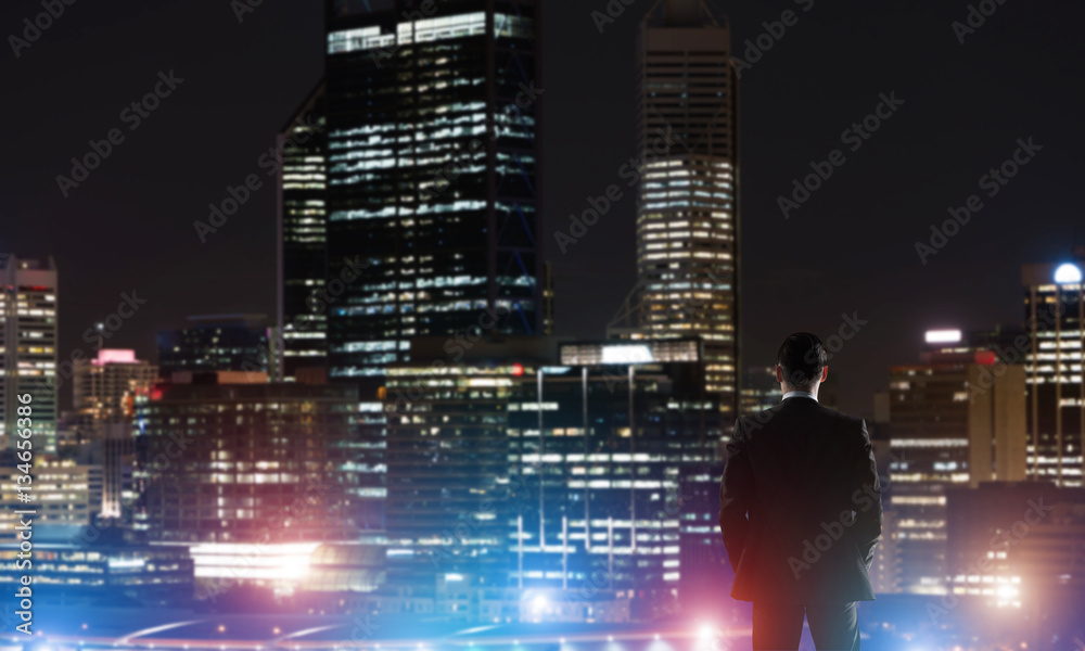 Businessman viewing night glowing city