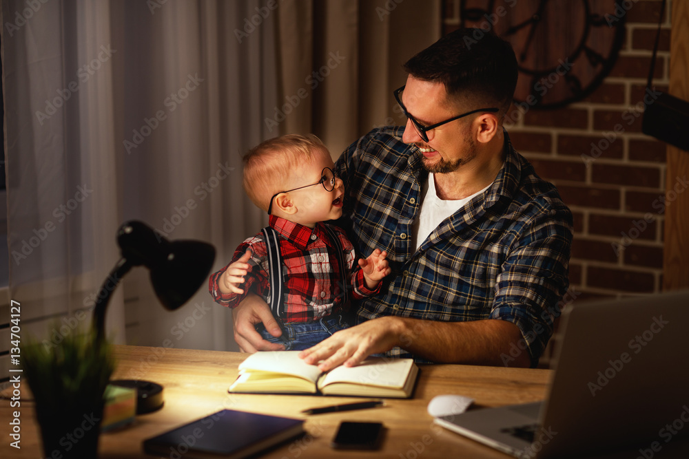 father and son baby work at home at computer in dark