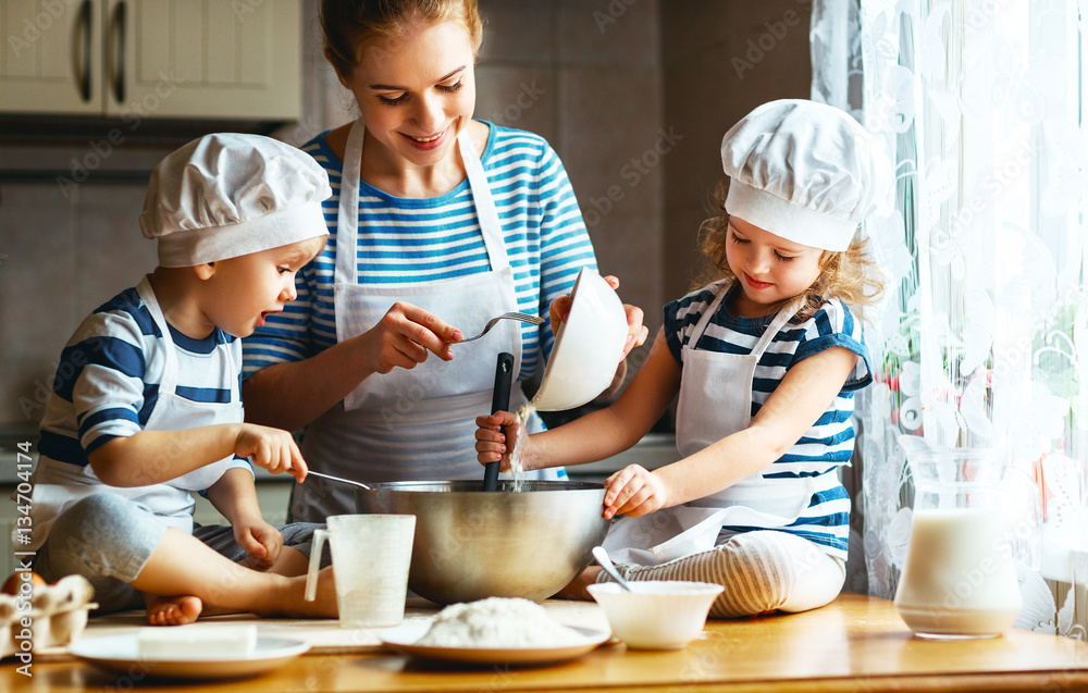 happy family in kitchen. mother and children preparing dough, ba