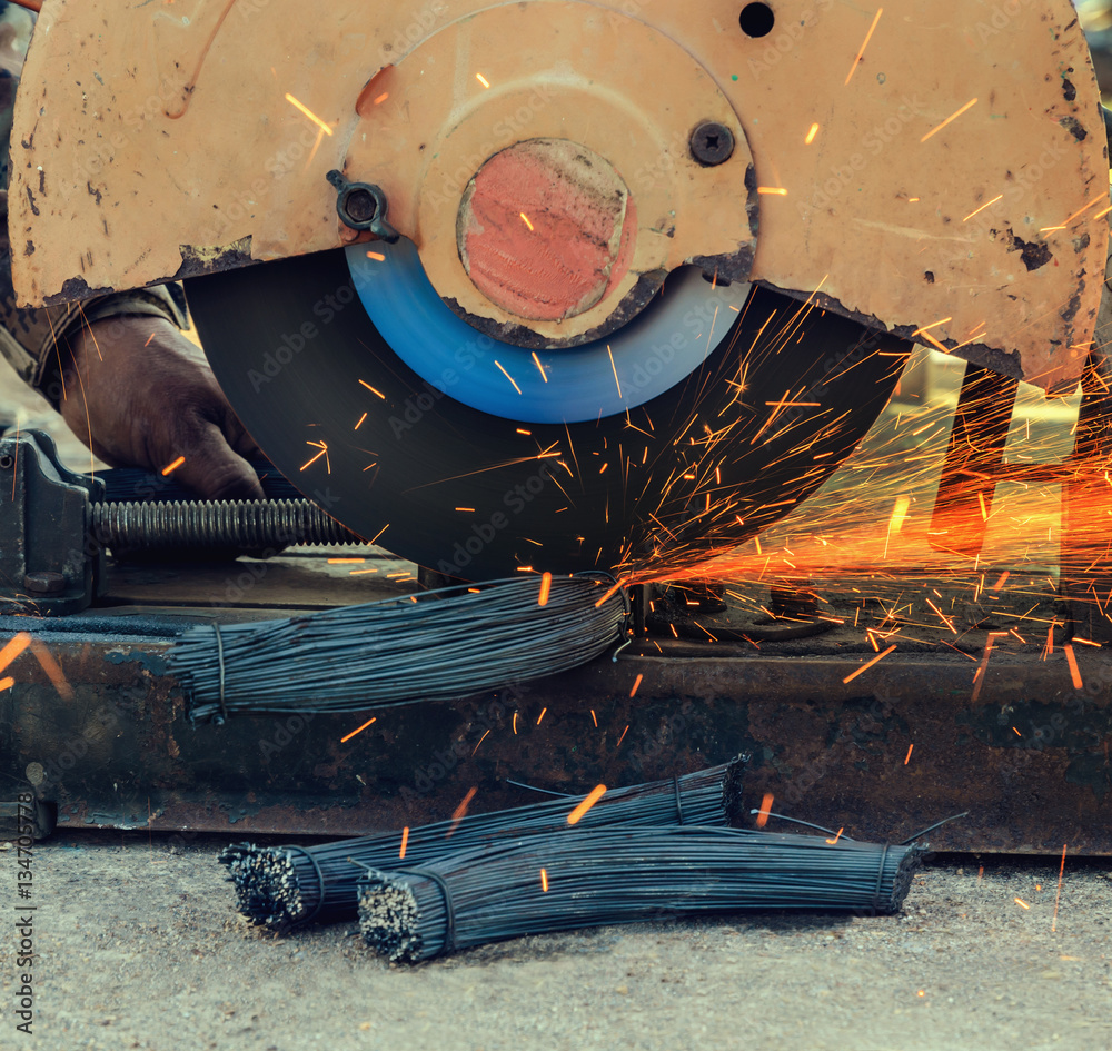 Worker cutting metal with grinder in construction site