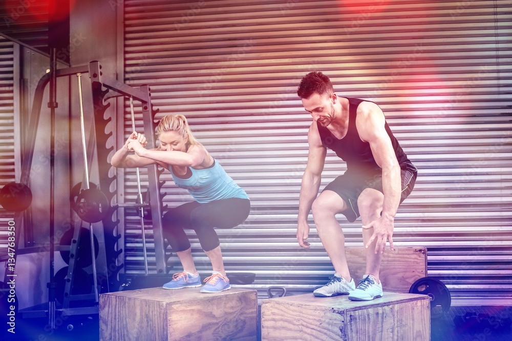 Couple doing box jumps in gym