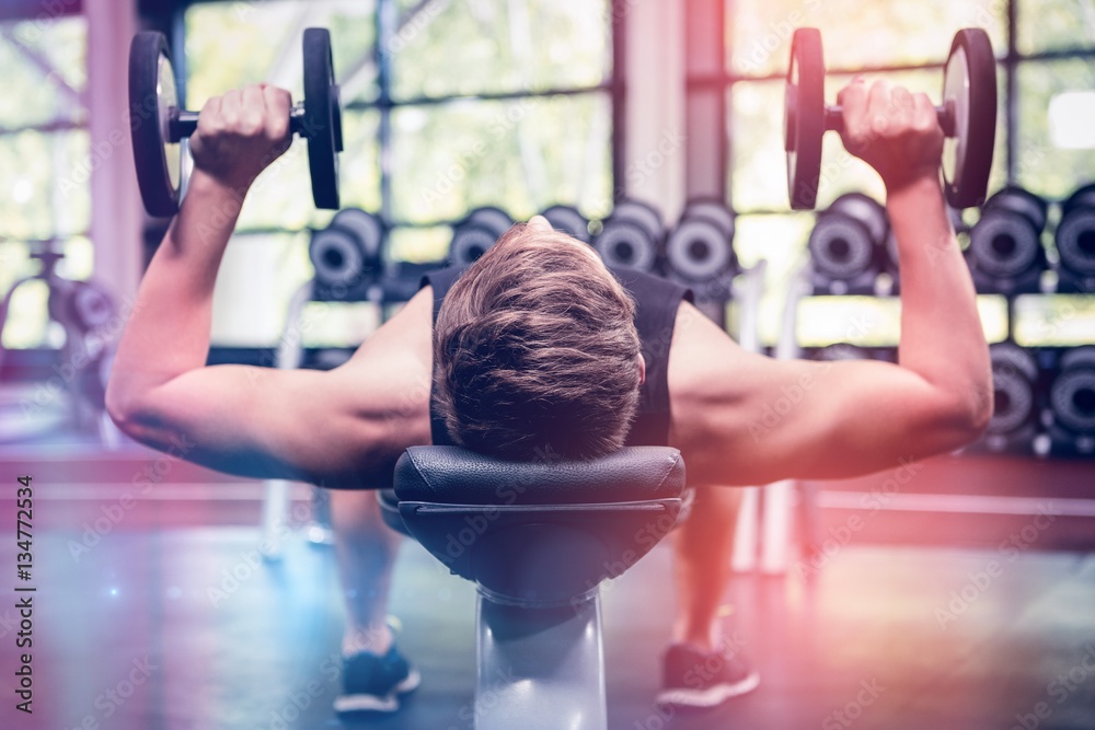 Man lifting dumbbell weights while lying down