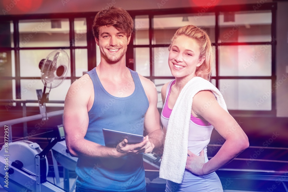 Portrait of trainer and woman standing with digital tablet