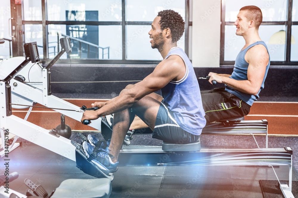 Muscular men using rowing machine