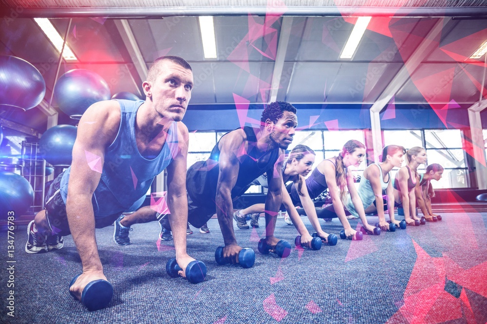 Fitness class in plank position with dumbbells