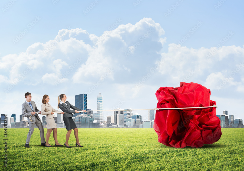 Young business people outdoors and huge paper ball as symbol of creativity