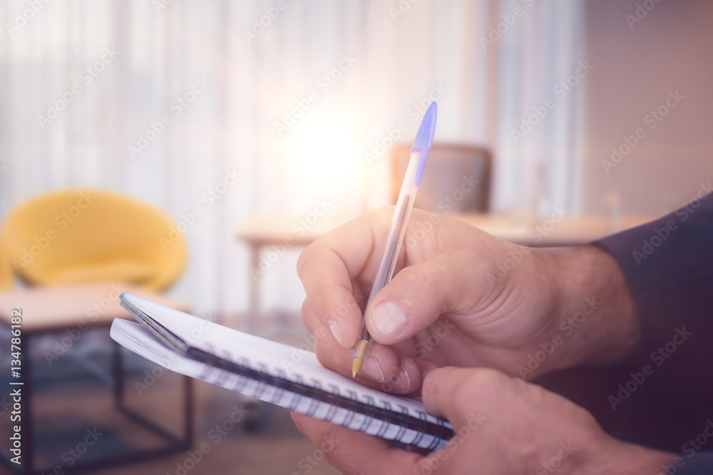 Composite image of close up of man writing in spiral book