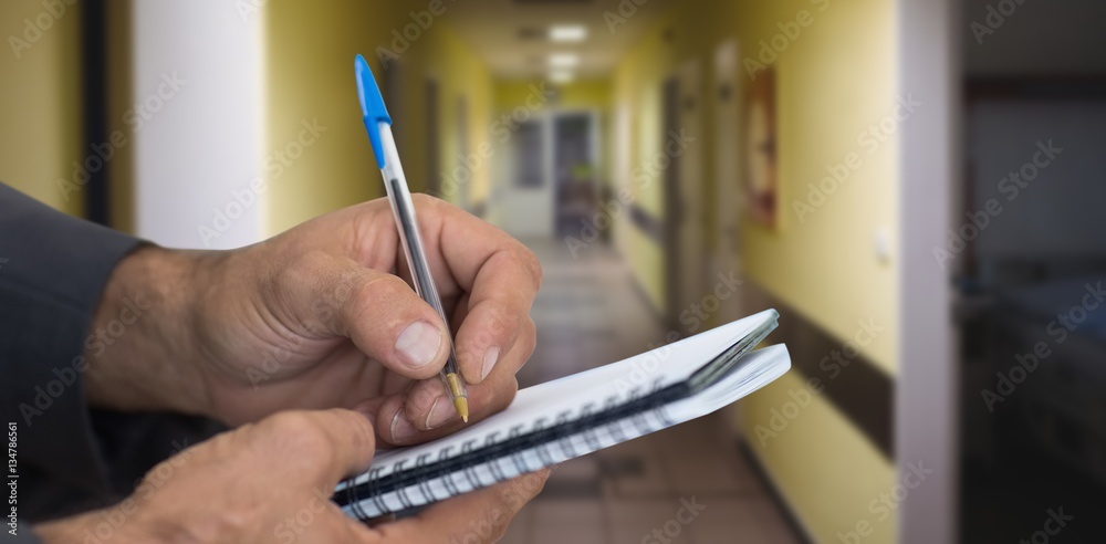 Composite image of close up of man writing in spiral book