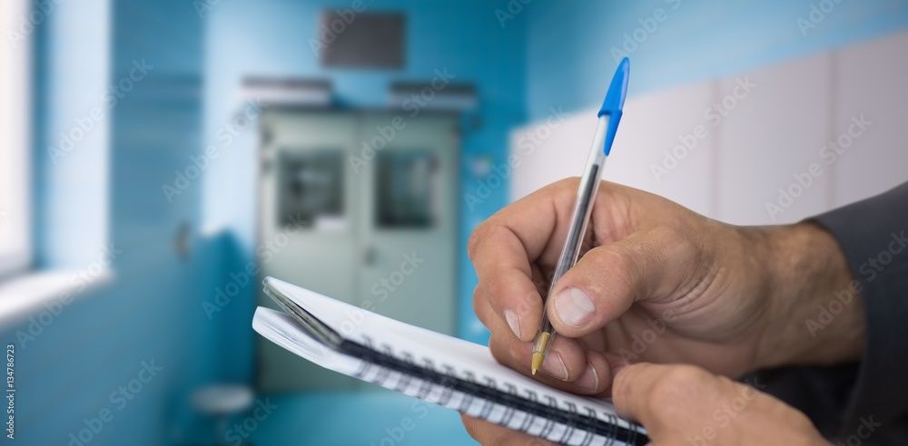 Composite image of close up of man writing in spiral book