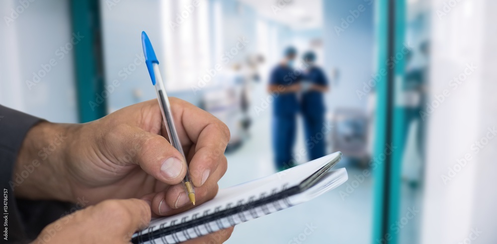 Composite image of close up of man writing in spiral book