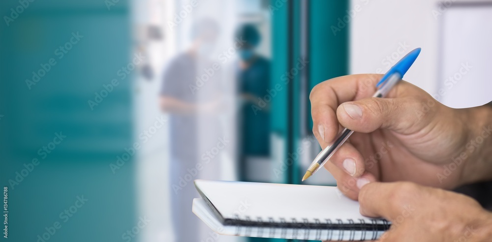 Composite image of close up of man writing in notepad